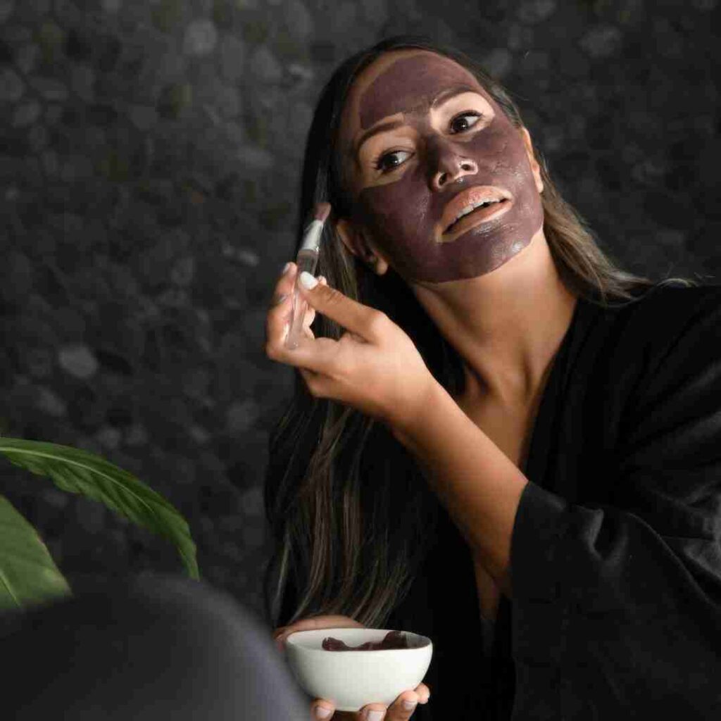 Woman using the purple face mask from koko body vegan skincare